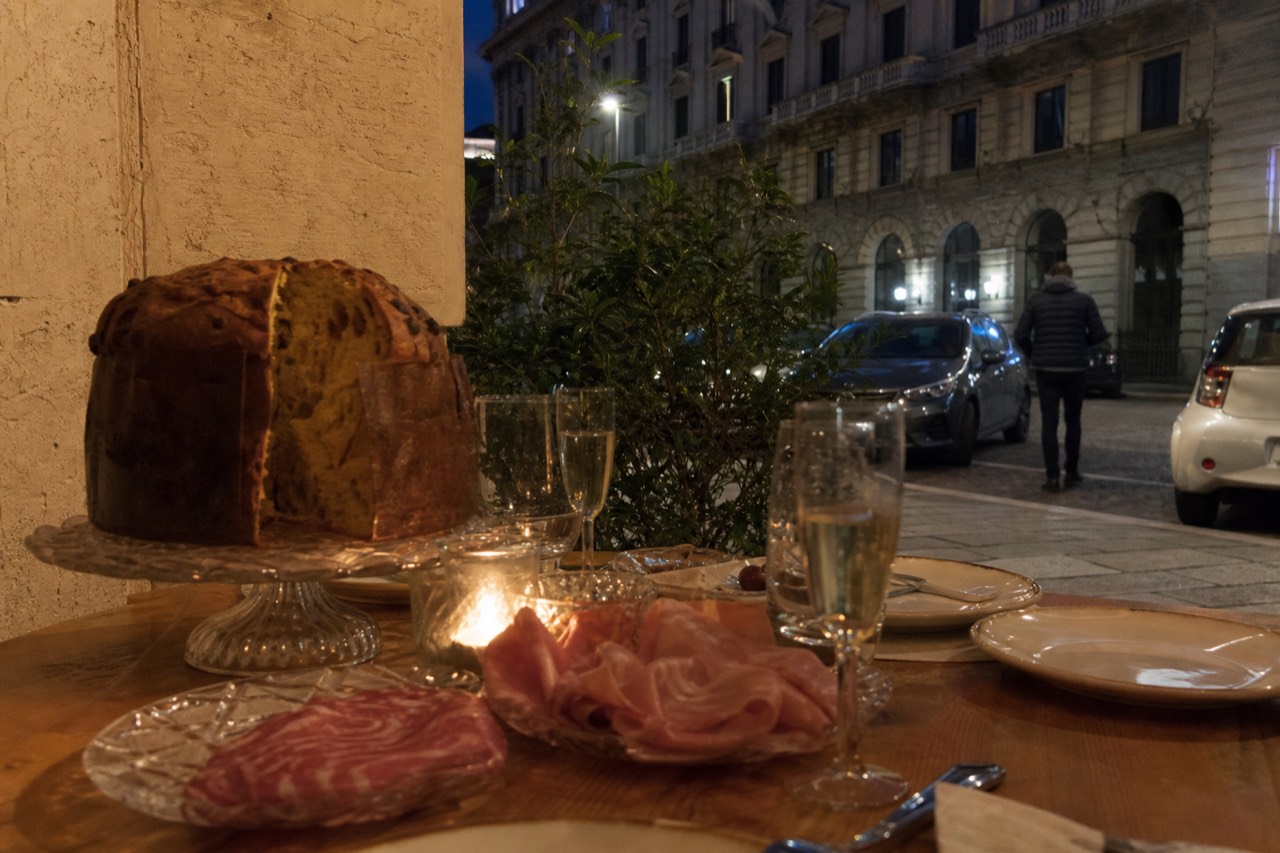 A Christmas table set with panettone, cured meats and glasses of spumante