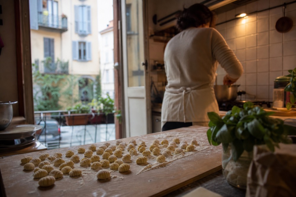 A cook's hands shaping gnocchi on a floured wooden board