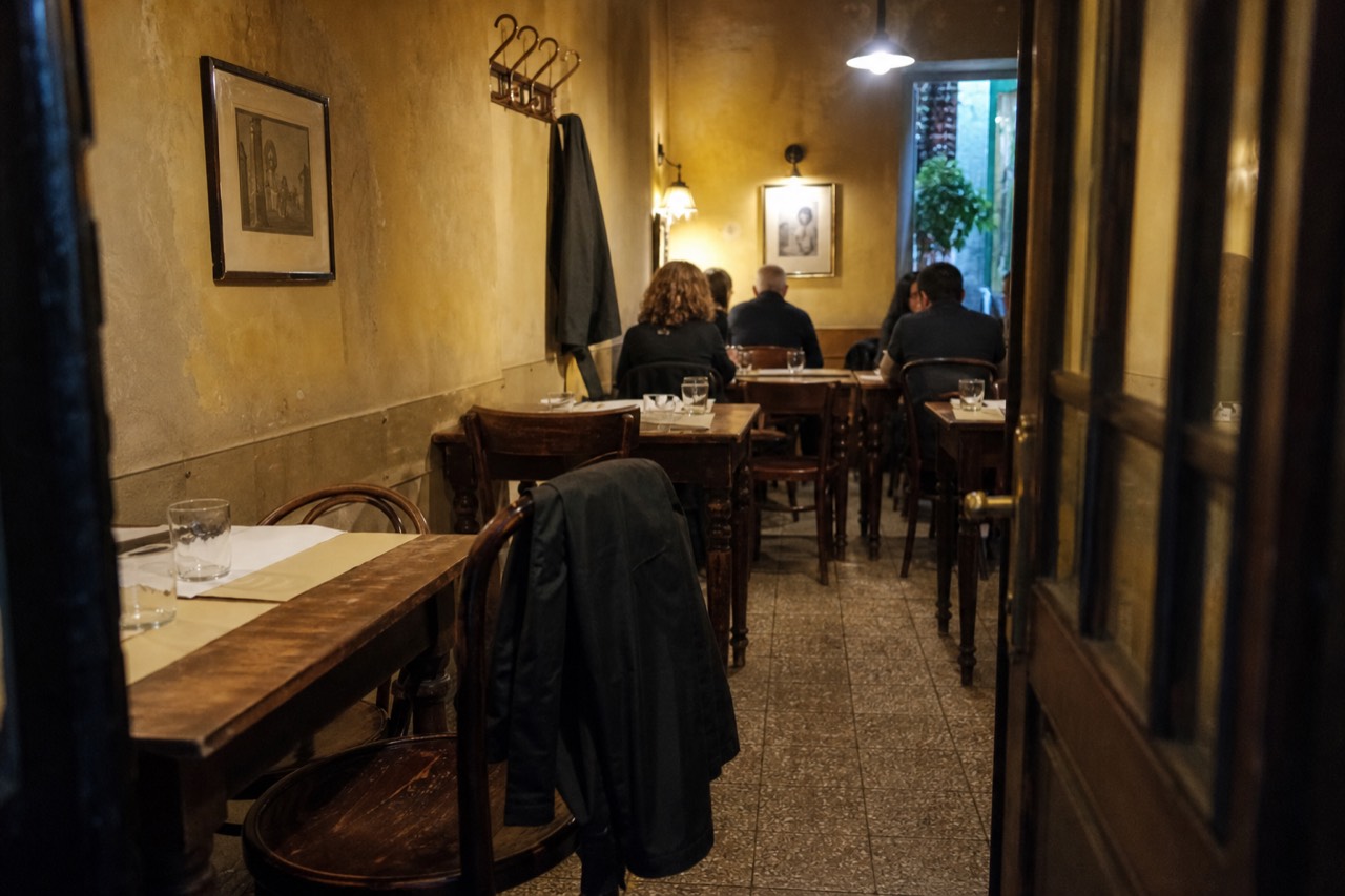 A small neighbourhood dining room with wooden tables, paper place mats and a chalkboard menu