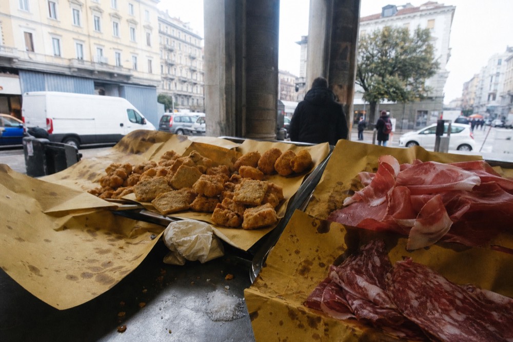 A spread of Italian street food on a market stall counter in Milan