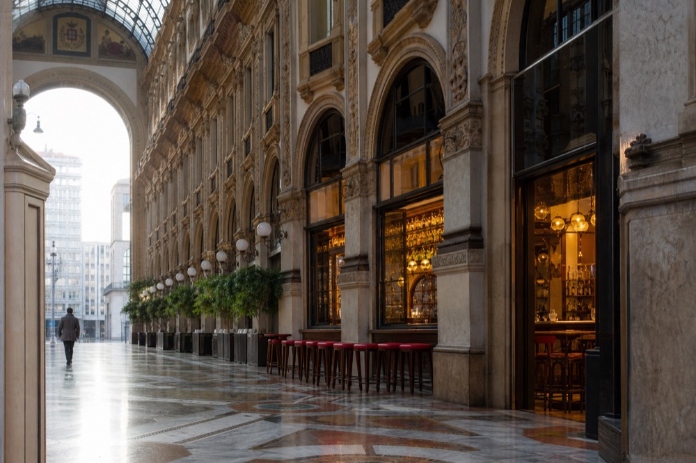Historic Camparino bar facade in the Galleria Vittorio Emanuele II with warm interior light and bar stools