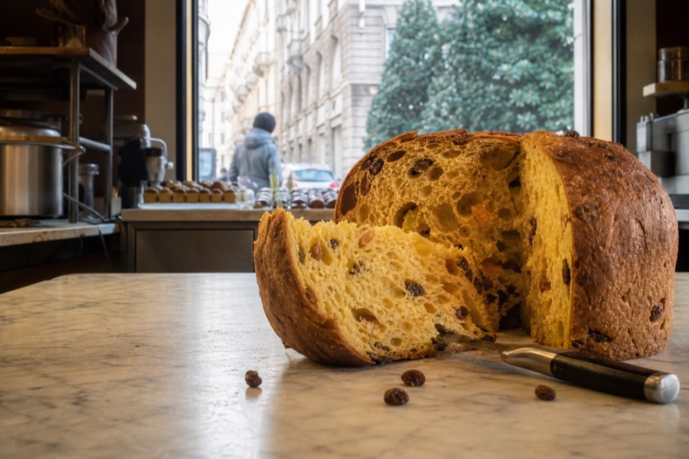 Sliced panettone showing its open elongated crumb with raisins and candied citrus peel