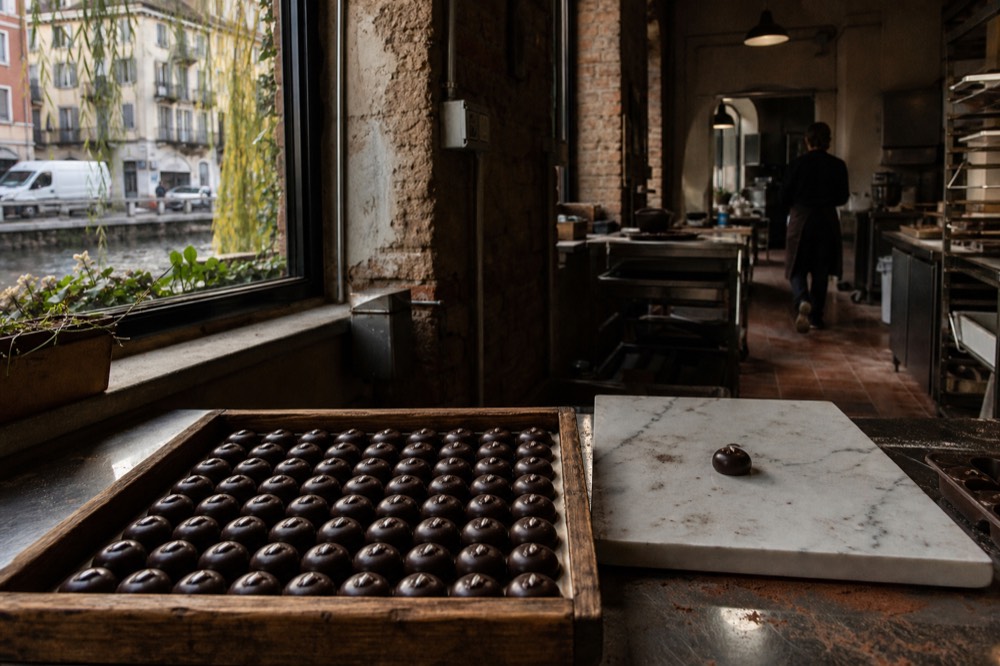 Rows of dark chocolate pralines arranged in a wooden tray at a chocolate workshop