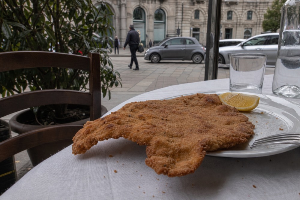 A breaded veal cutlet with lemon on a white plate in a Milan restaurant