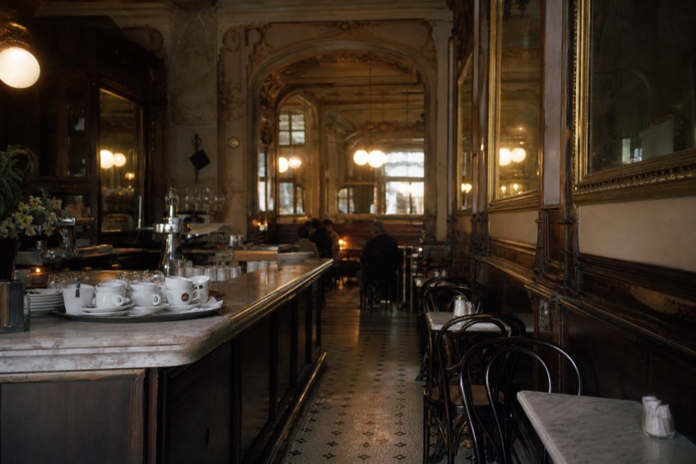 Historic cafe interior with mirrored walls and a marble counter in central Milan