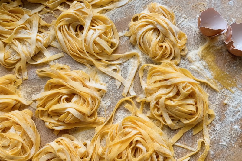 Nests of fresh egg tagliatelle on a floured board at a Milan pasta class