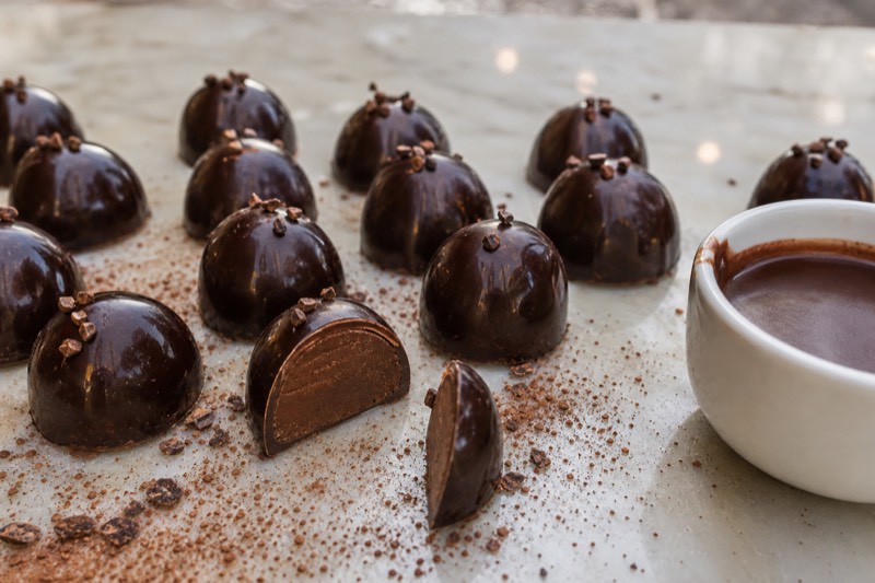 Dark chocolate pralines cooling on a marble slab in a Milan chocolate workshop