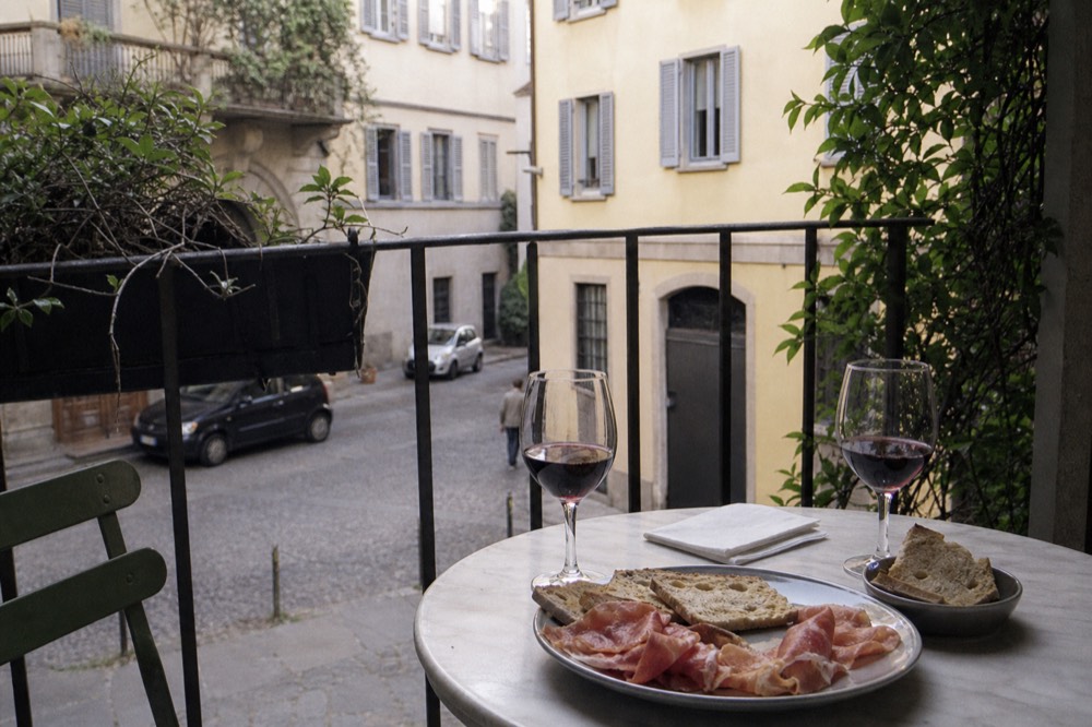 Two glasses of red wine on a small table beside a plate of cured meats and bread