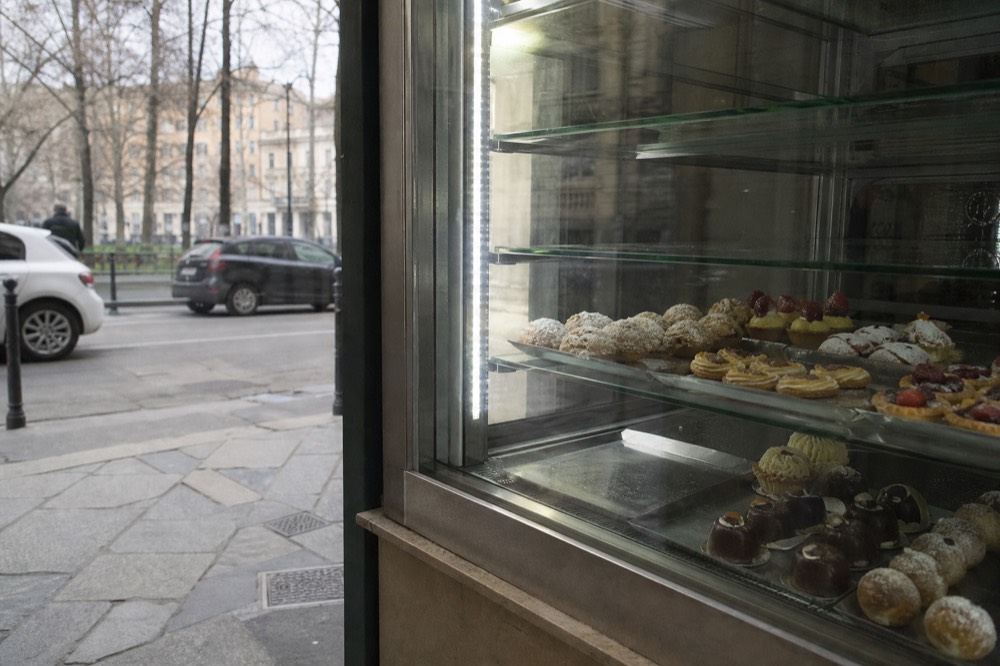 Assortment of small pastries arranged in a glass display case in a Milan bakery