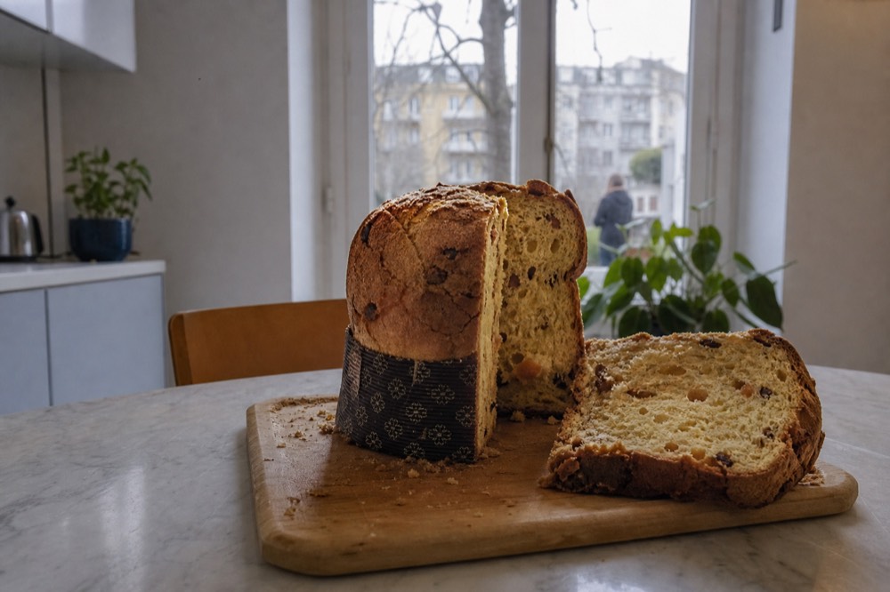 Sliced panettone with an open crumb and cracked top crust on a wooden board