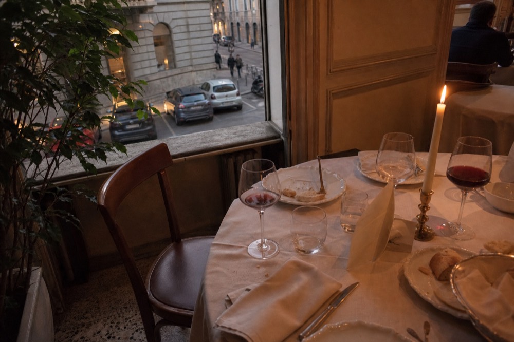 Restaurant table with wine glasses, bread and a menu on a white tablecloth