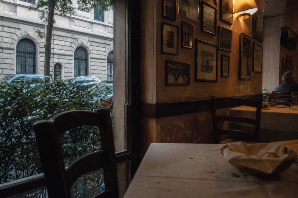 Old-fashioned trattoria dining room with wooden chairs and framed pictures on the walls
