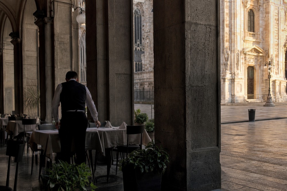 Waiter setting tables in an empty restaurant before service