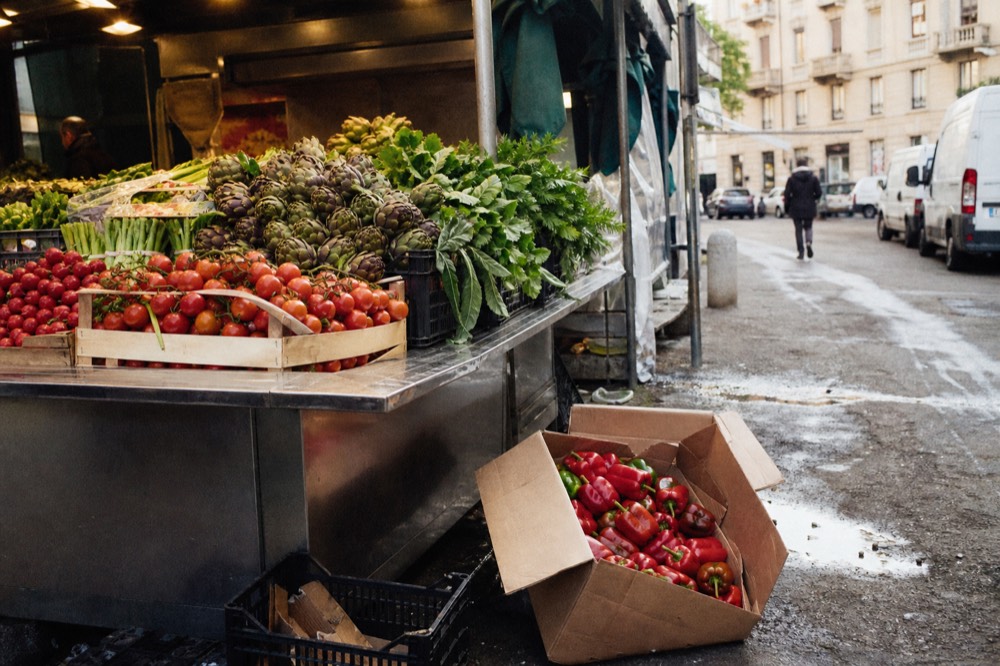 A market stall displaying fresh vegetables and baskets of produce under warm lights