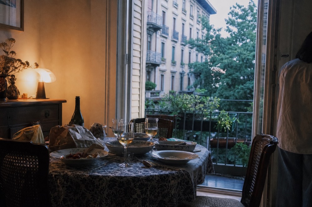 A home dining table set with wine glasses, bread and serving dishes