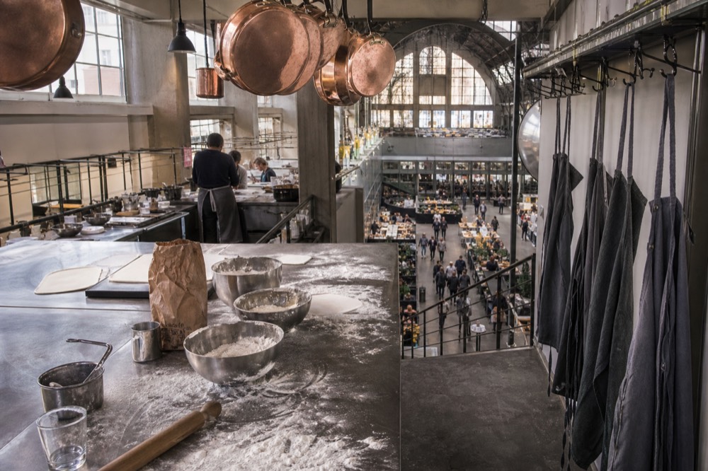 A Milan cooking school interior with workstations, aprons and hanging pans