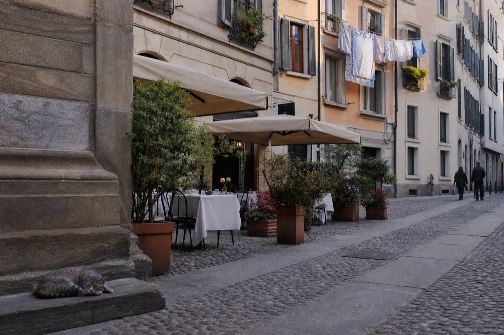 A quiet cobblestone lane with small restaurant awnings a short walk from the cathedral