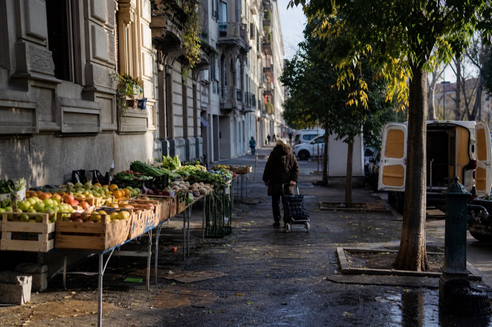 Milan street market stalls with crates of fruit and vegetables in morning light