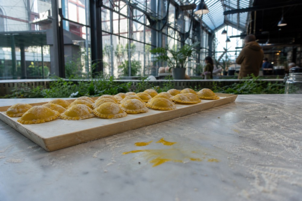 A tray of fresh filled pasta on a marble counter inside a Milan food hall