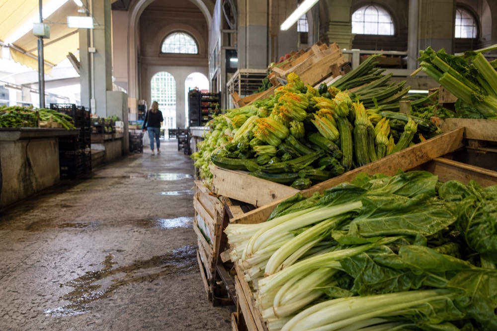 Fresh vegetables stacked in crates at an indoor Milan market stall