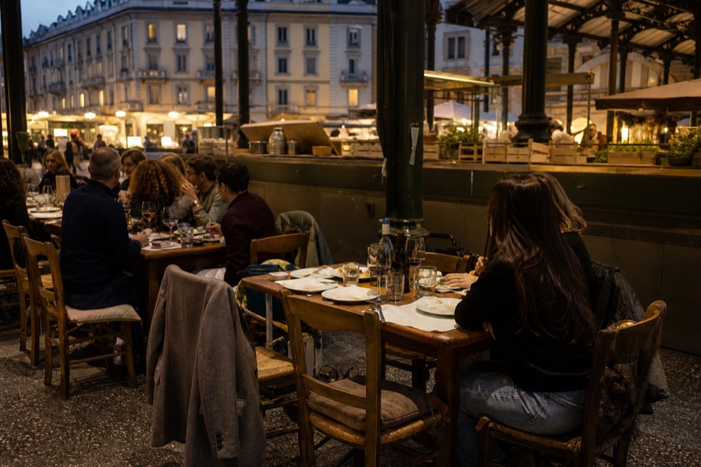 Diners seated at wooden tables beside market stalls