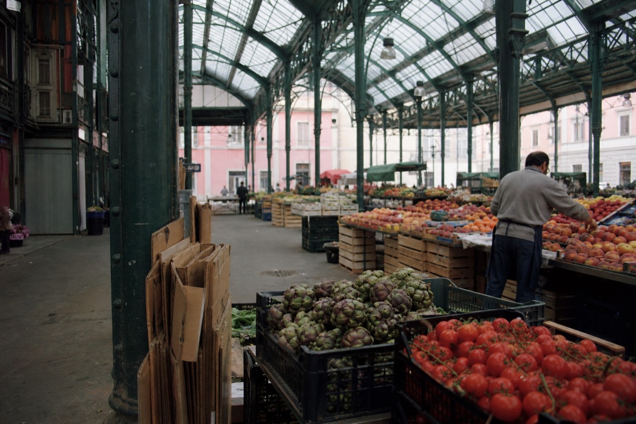 Produce stalls under the iron roof of a Milan covered market