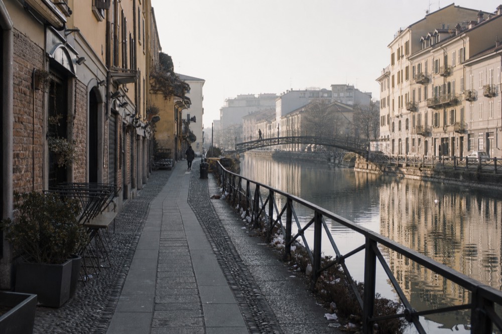 A quiet canal bank in morning light with shuttered bar fronts