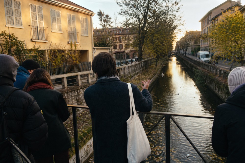 A guide speaking to a small group on a bridge over a Milan canal