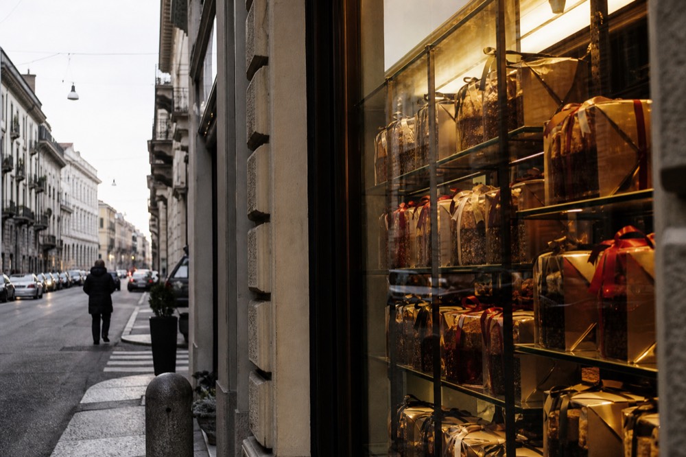 Shelves of boxed panettone from several pastry brands arranged in a Milan shop display
