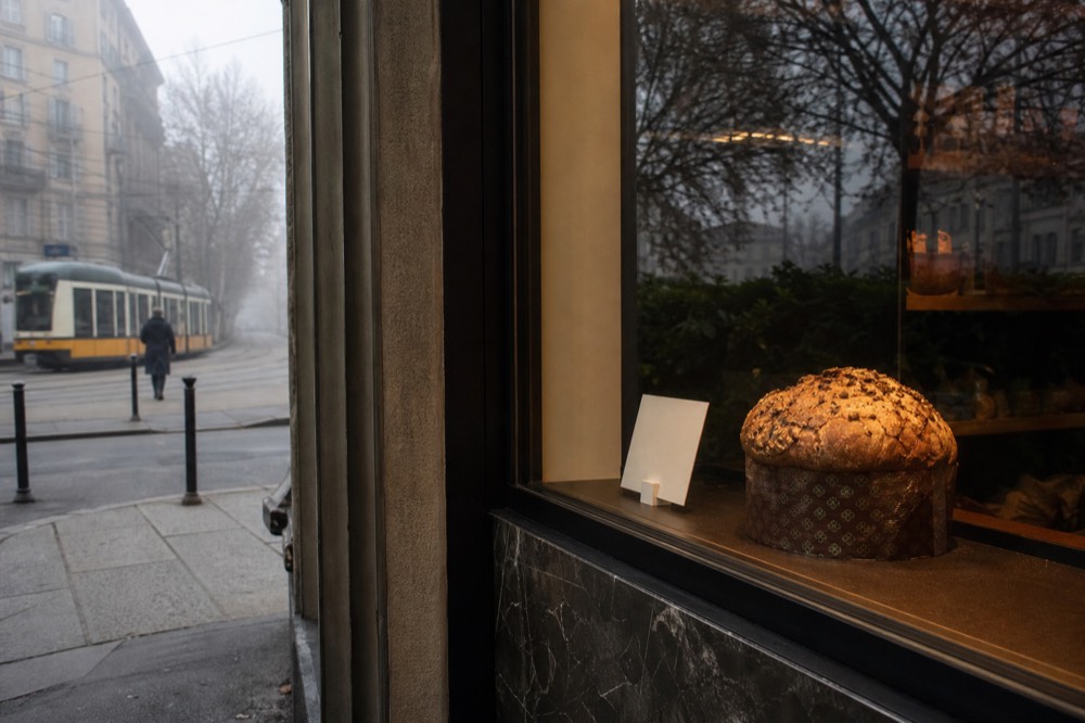 A price tag beside a whole artisan panettone on display in a Milan pastry shop window
