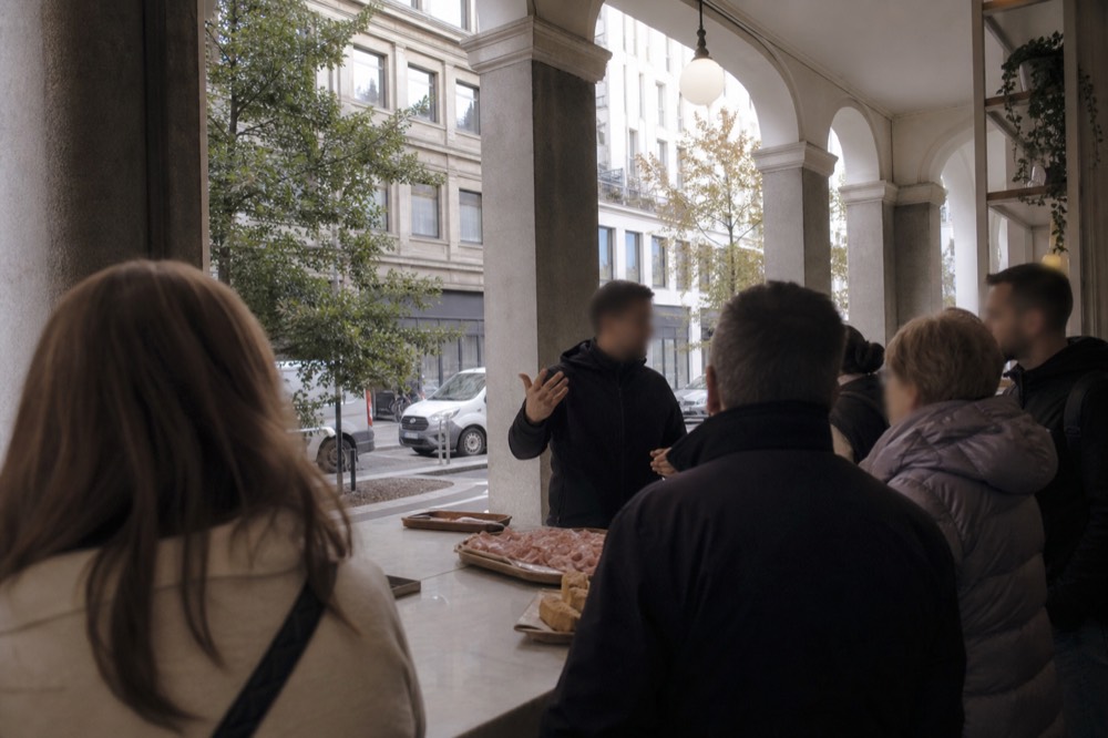 A guided food tour group gathered around a market counter in Milan