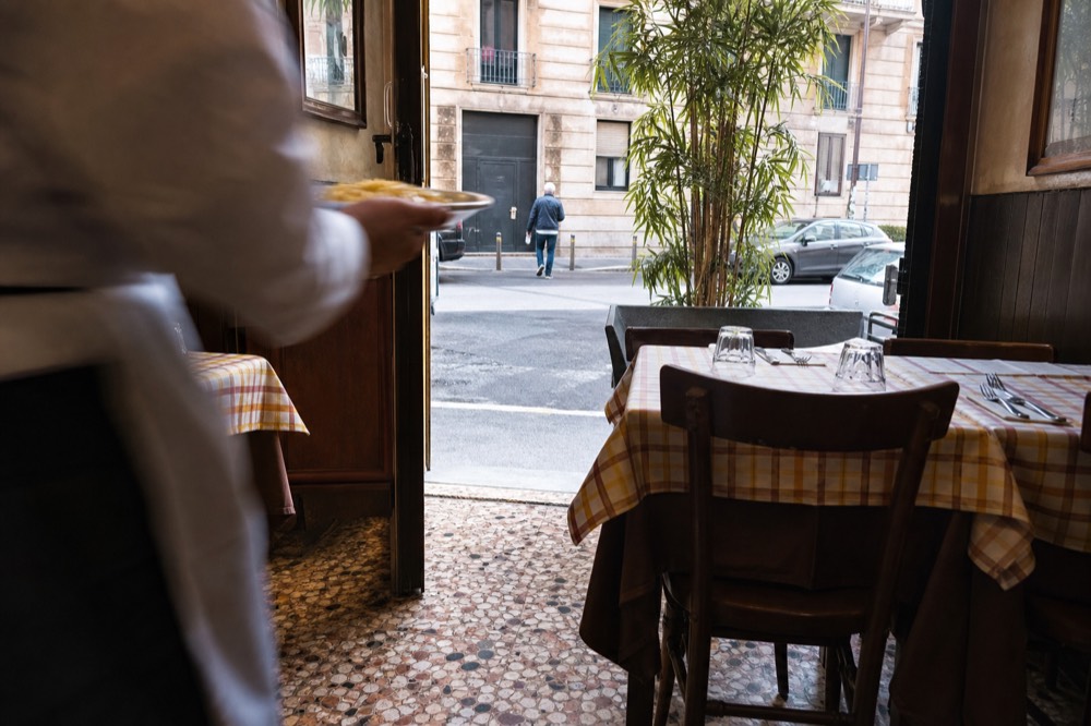 A trattoria dining room with set tables and a risotto plate being served