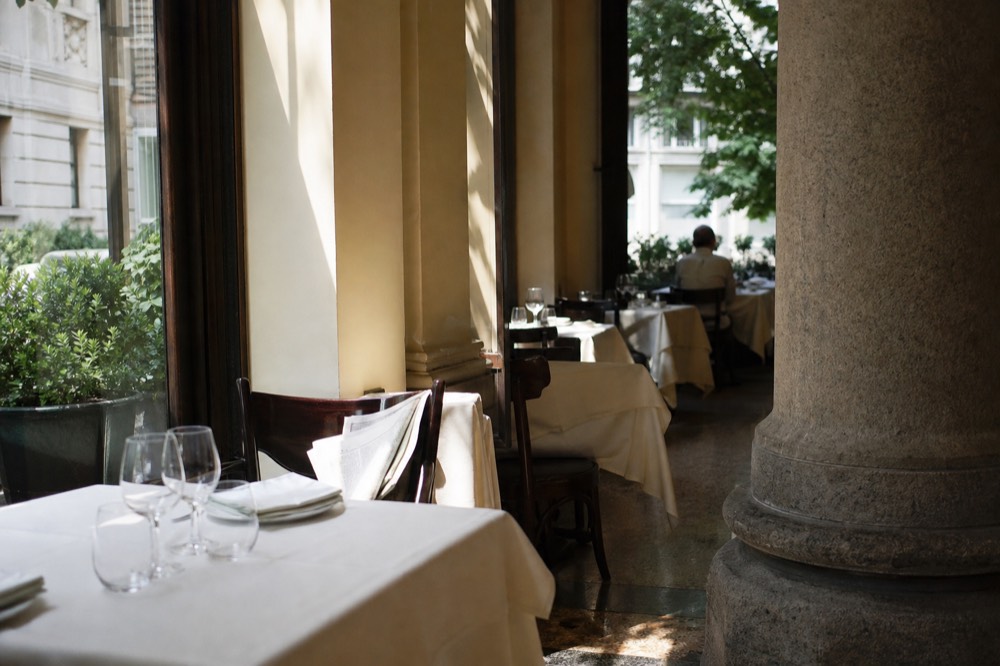 A Milan restaurant interior at lunchtime with tables set for service