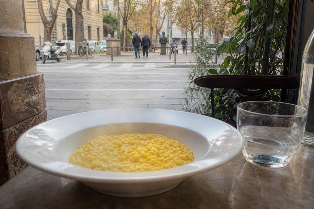 A bowl of golden saffron risotto alla milanese on a restaurant table