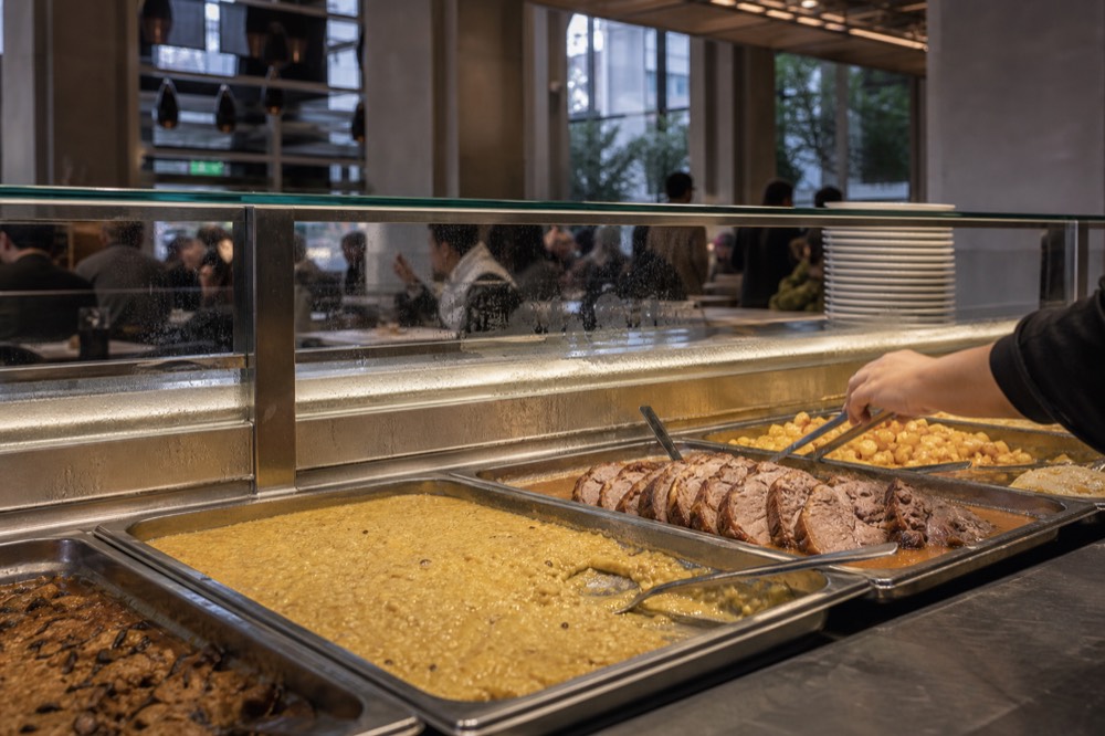 A food hall counter with prepared Italian dishes displayed under lights