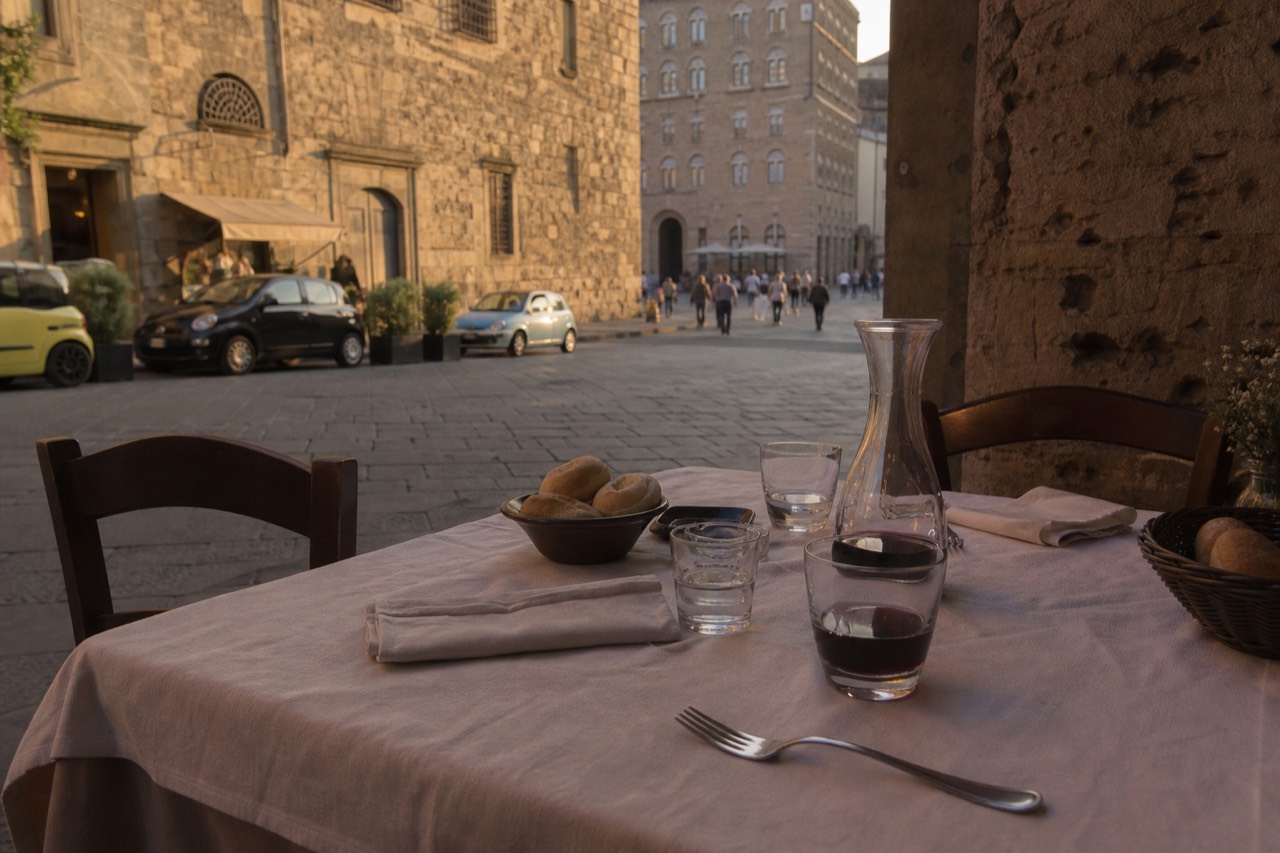 A Milanese trattoria table set with bread, water glasses and a carafe of red wine